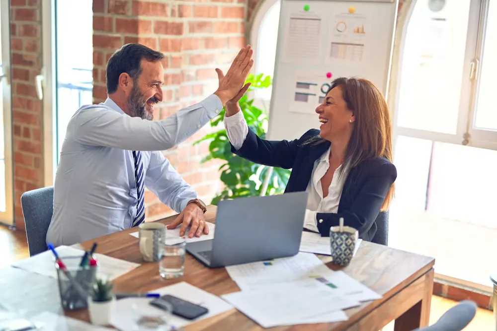 Two colleagues celebrating at a desk